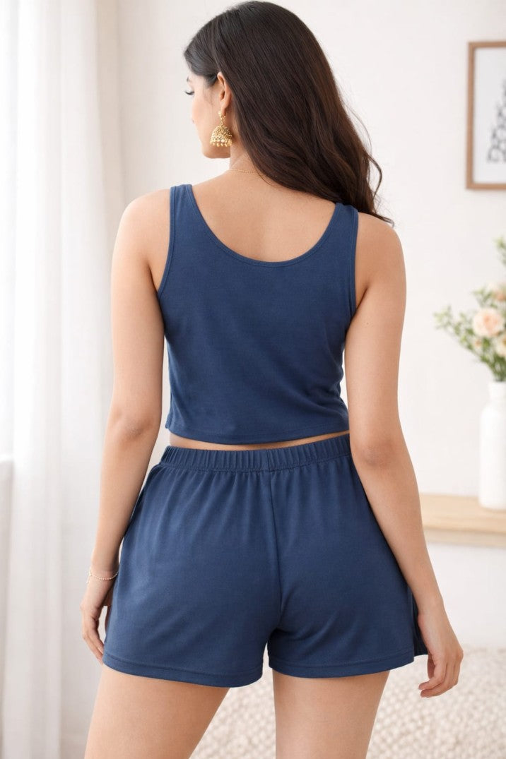 Woman wearing a blue tank top and shorts set in a room with a light background